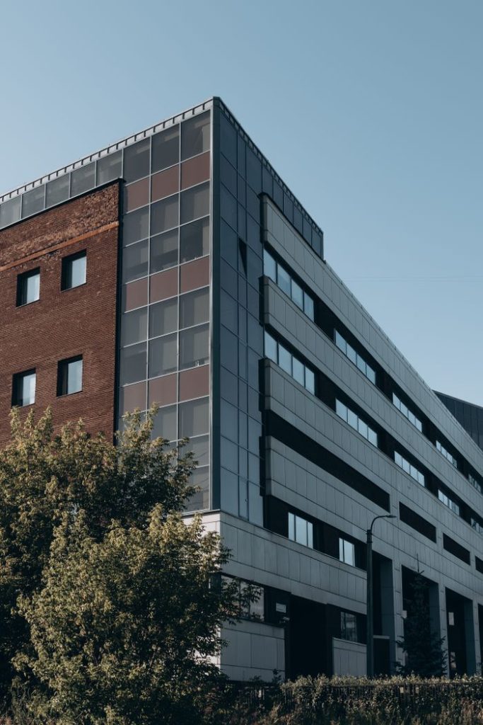 Contemporary urban building blending brick and metal architecture with greenery.